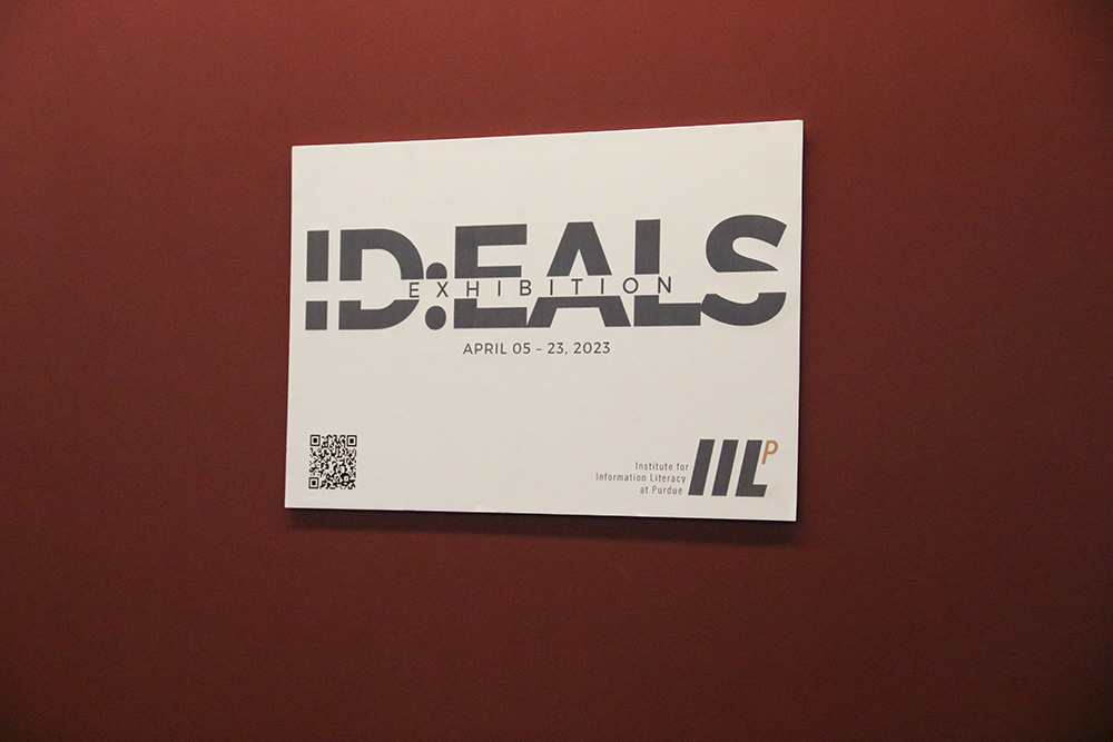 A white sign on a red wall that reads, "ID:EALS Exhibition. April 05 - 23, 2023."