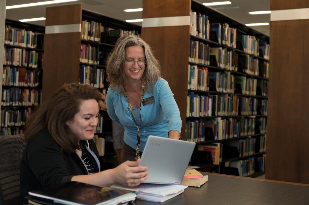 Libraries staff helping a patron in a collection area.
