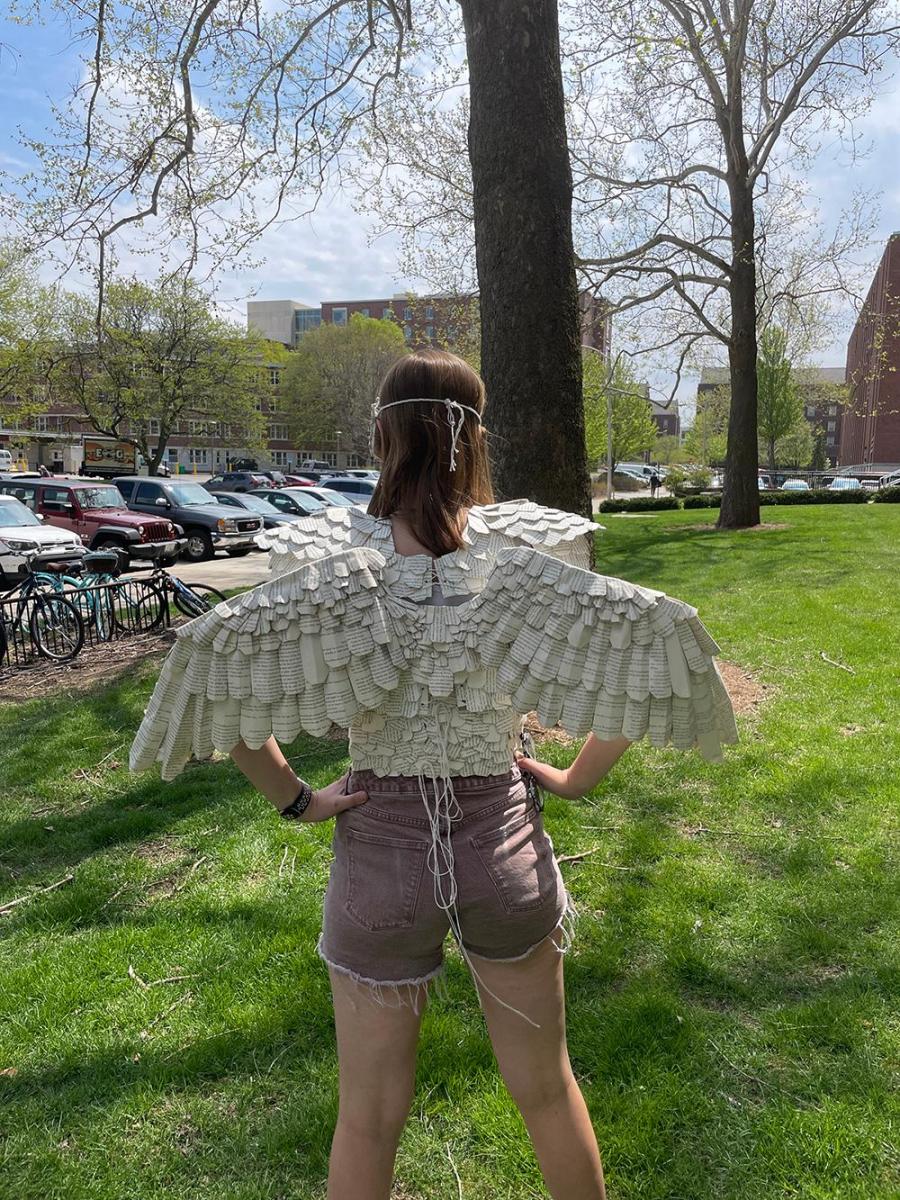 Megan Miltimore modelling the Owl Warrior wearable sculpture. This photo is a back view featuring the wings with feathers cut from book pages.